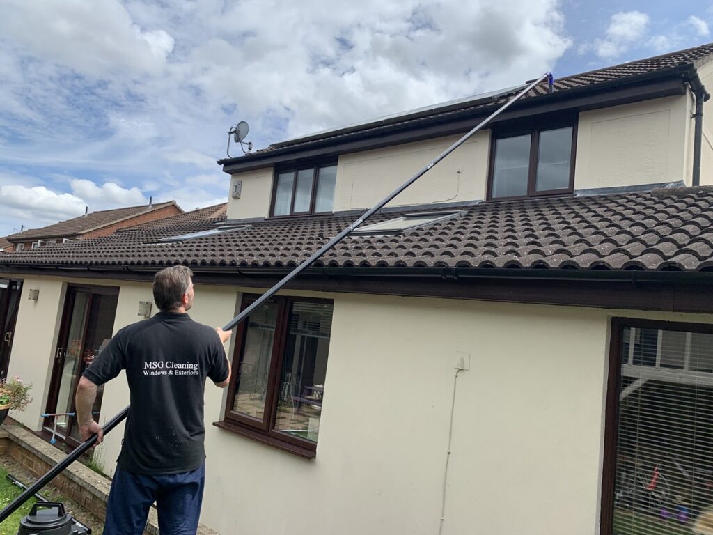 reaching over the single storey extension to clean the gutters